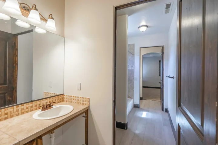 Bathroom vanity with an oval sink, tile countertop, and mosaic tile backsplash