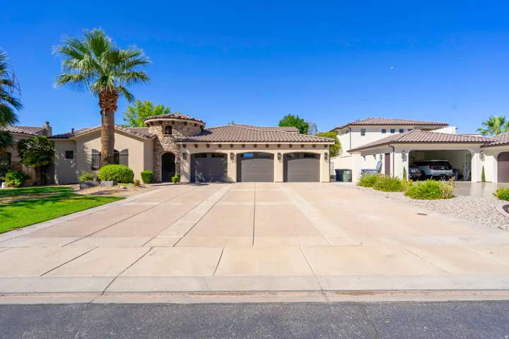 Stucco exterior with stone accents, a tile roof, and a three-car garage