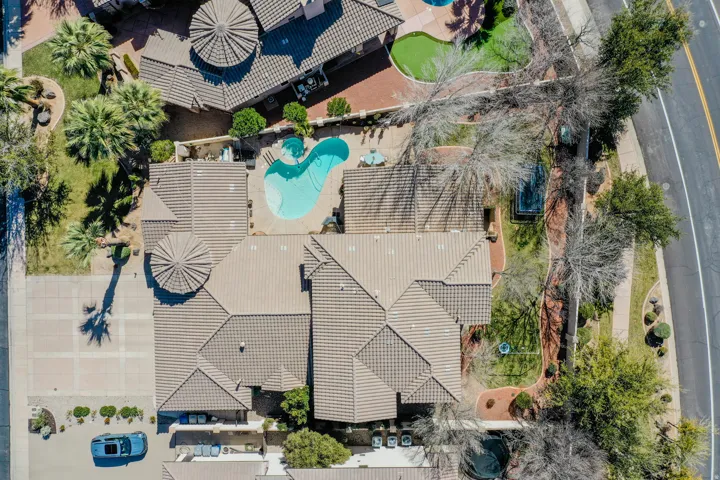 Expansive property featuring a multi-level tiled roof, a large freeform swimming pool, and mature palm trees