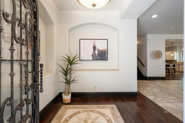 Wrought iron entry door, wood-finish flooring, recessed wall niche, and an illuminated ceiling fixture