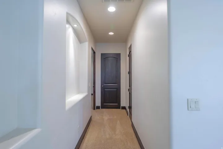 Recessed wall niche with accent lighting, light-toned carpet flooring, dark wood-finish doors, and recessed ceiling lighting
