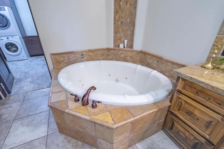 Built-in jetted tub with corner installation and bronze-finish fixtures
