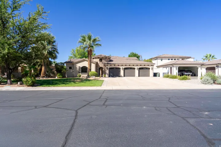Stucco exterior with a tile roof, an arched entryway, a three-car garage, and desert-adapted landscaping