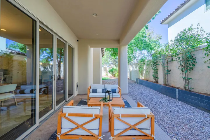 Covered patio featuring recessed lighting, a concrete slab, a gravel-filled side yard, and a privacy wall with plantings