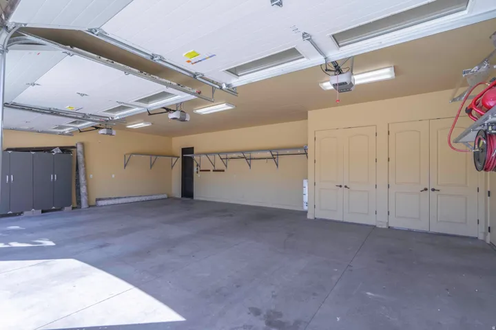Spacious garage with multiple overhead doors, concrete flooring, and built-in shelving,