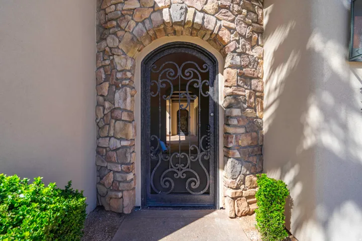Arched stone entryway with an ornate wrought iron security door