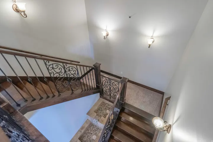 Staircase with wood-finish treads and risers, decorative wrought iron balusters, and a wood-finish handrail