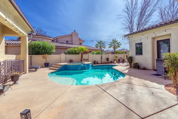 Resort-style backyard featuring a custom-shaped swimming pool with a spa, and a covered patio