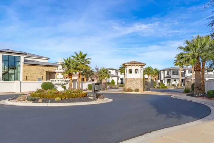 Circular driveway entrance featuring a tiered fountain, mature palm trees, and stone-clad gatehouse with a tiled roof
