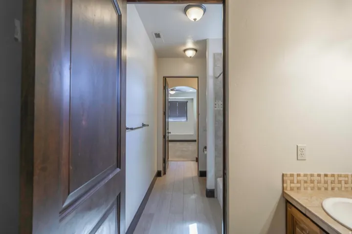 Archway entry with recessed lighting, wood-finish flooring, and built-in vanity with tiled backsplash