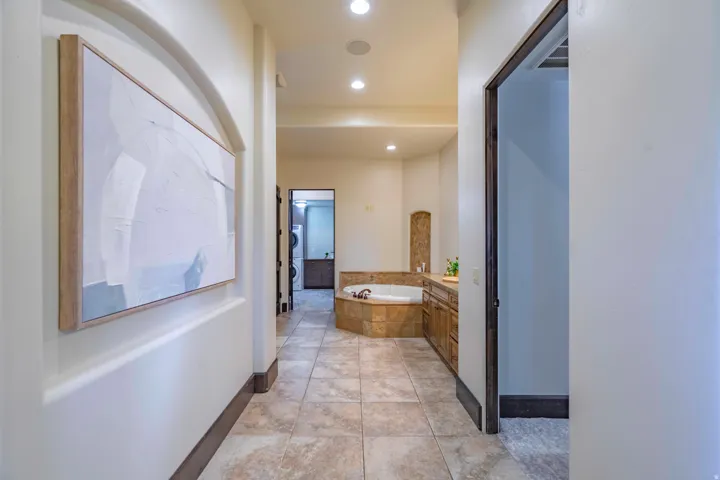 Archway entry, recessed lighting, tile flooring, built-in soaking tub, wood-finish cabinetry