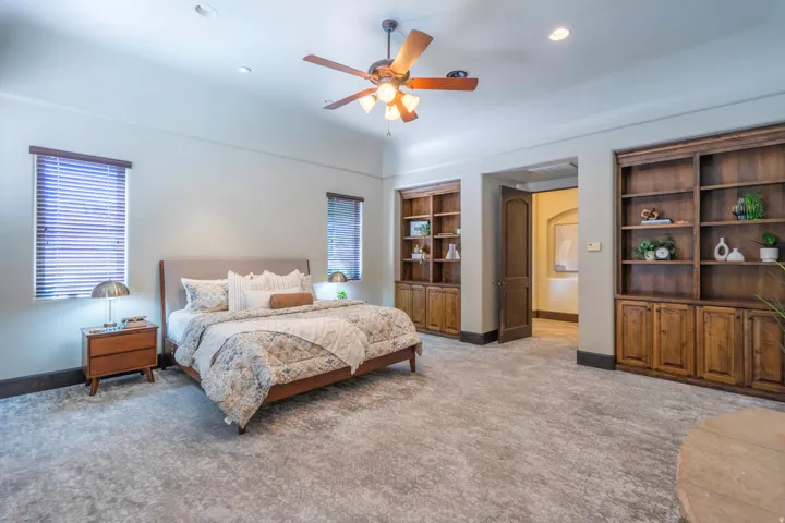 Spacious room featuring a ceiling fan with integrated lighting, recessed lighting, and two built-in wood-finish shelving units with lower cabinetry