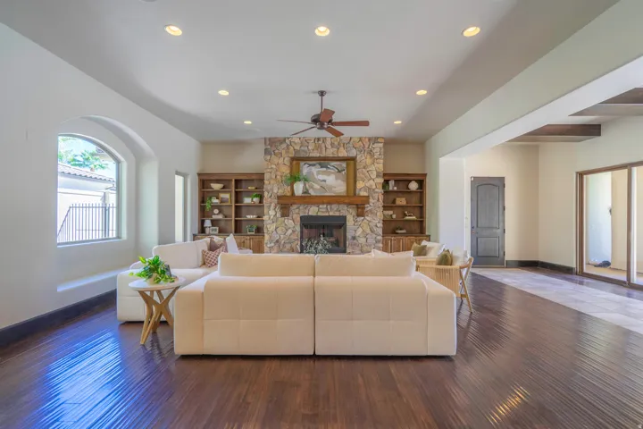 Hardwood flooring, recessed lighting, stone-clad fireplace, integrated shelving, and a ceiling fan