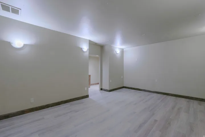 Spacious interior with light wood-finish flooring, recessed lighting, and wall sconces