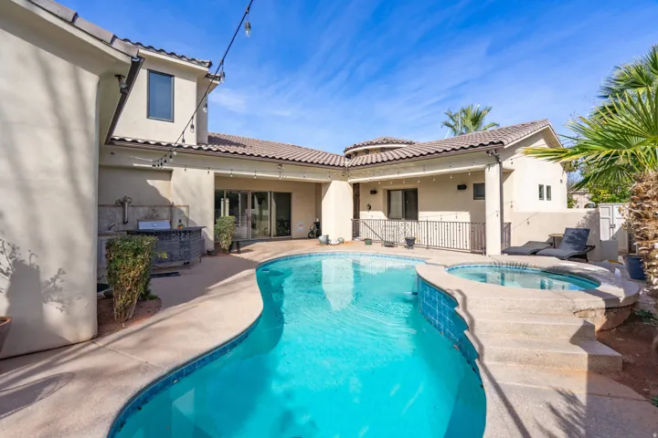 Swimming pool with integrated spa and tiled accents, complemented by an outdoor kitchen and tiled roofline