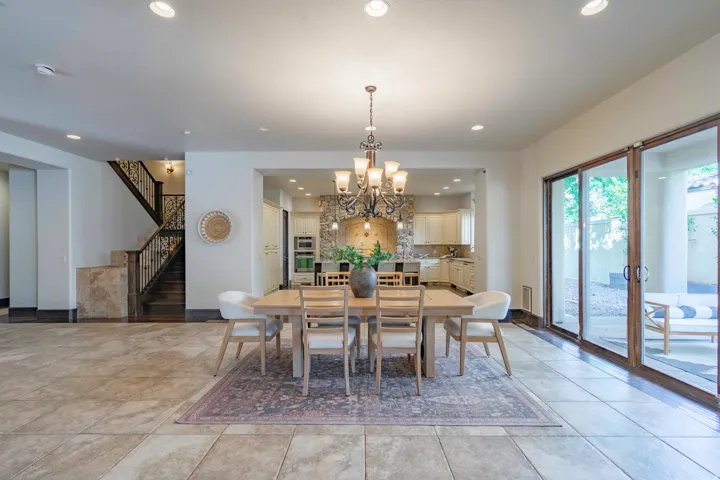 Spacious interior featuring large format tile flooring, a multi-pane sliding glass door, recessed lighting, and a detailed wood and wrought iron staircase