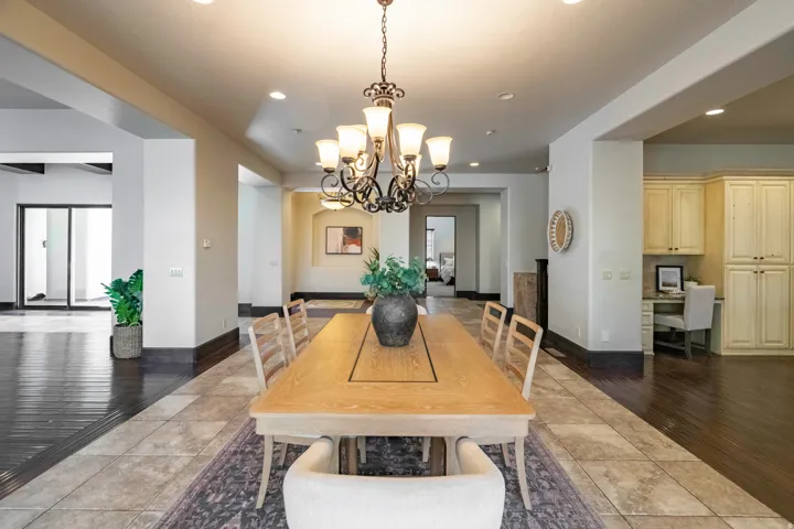 Spacious dining area featuring a prominent chandelier, tile flooring, and recessed lighting