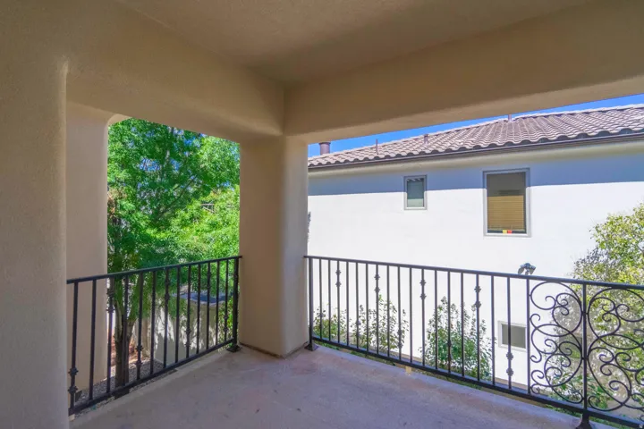 Covered balcony featuring black wrought iron railings with decorative scrollwork