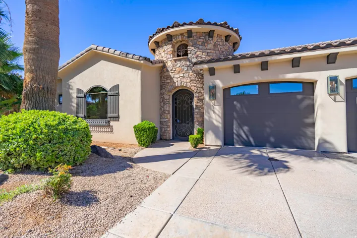 Stucco exterior with stone accents, arched windows with shutters, and a prominent stone turret entry