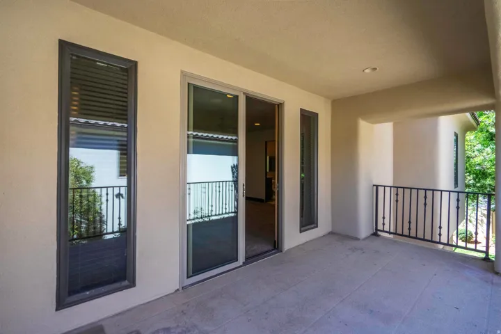 Covered balcony featuring a sliding glass door, recessed lighting, and an ornamental metal railing