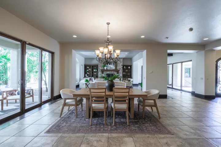 Tiled flooring, wrought iron chandelier, recessed lighting, expansive glass sliding doors, and a stone-clad fireplace surround