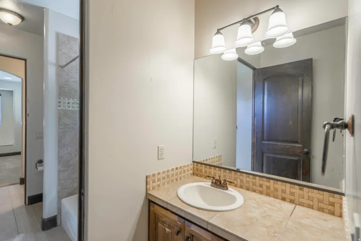 Vanity with integrated sink, tile countertop, and mosaic tile backsplash