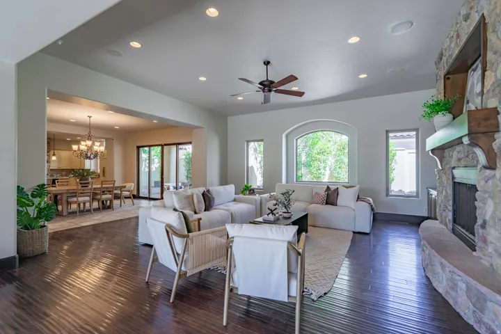 Spacious living area featuring wood-finish flooring, a stone fireplace, recessed lighting, and a ceiling fan