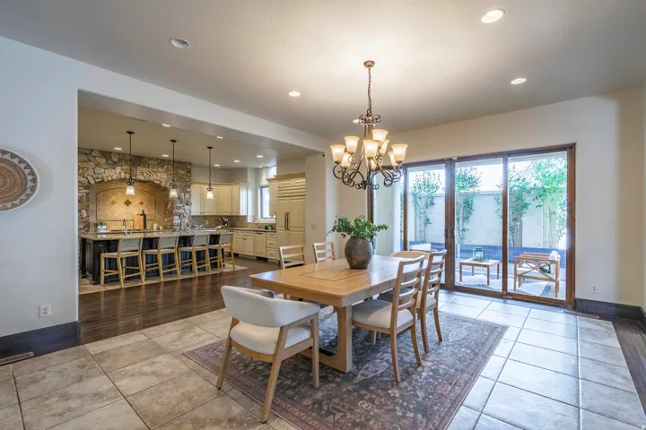 Spacious dining area with tile flooring, an ornate chandelier, and large sliding glass doors providing access to an outdoor area