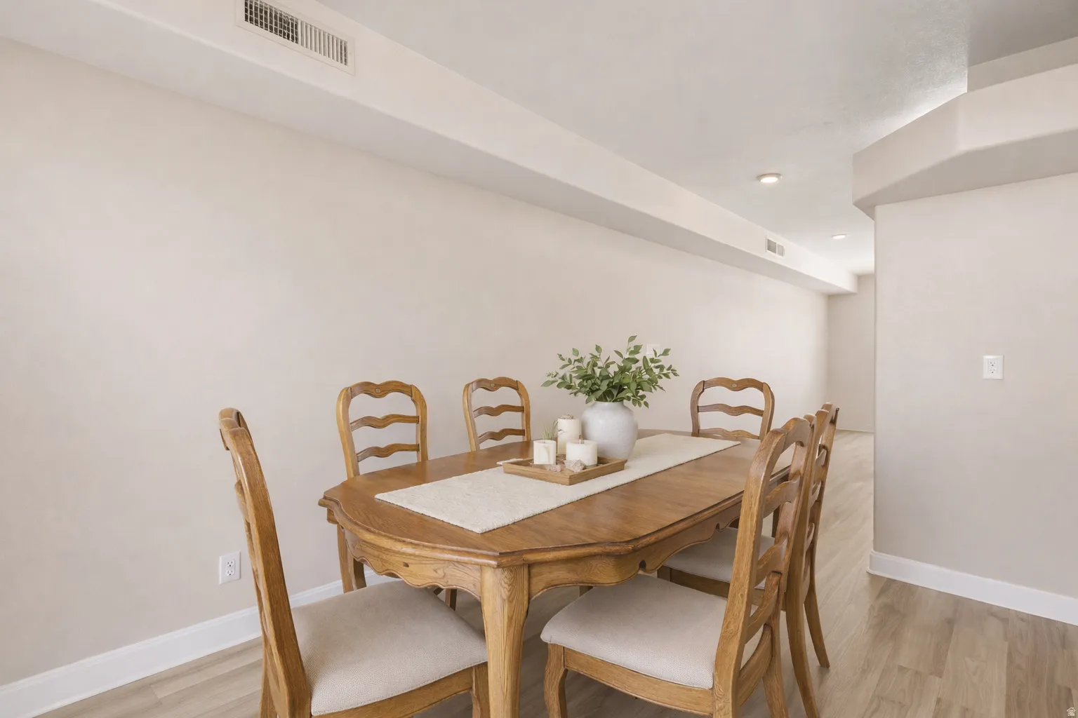 Recessed lighting illuminates the neutral-toned walls, complemented by wood-finish flooring and white trim
