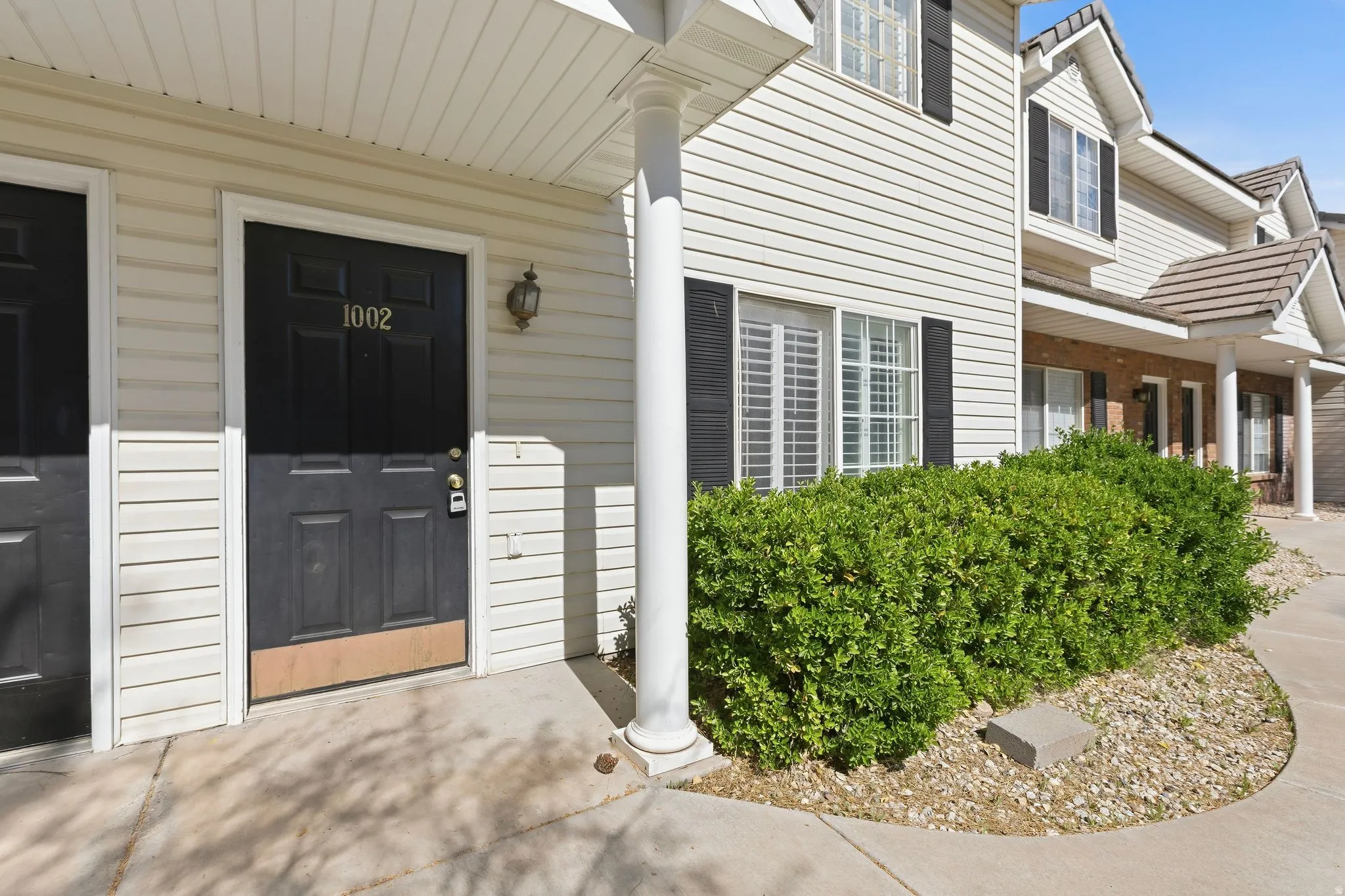 White siding exterior with black shutters and a black paneled entry door