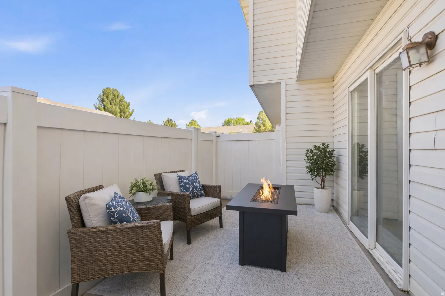 Private outdoor patio with a white privacy fence, light-colored concrete flooring, and a sliding glass door
