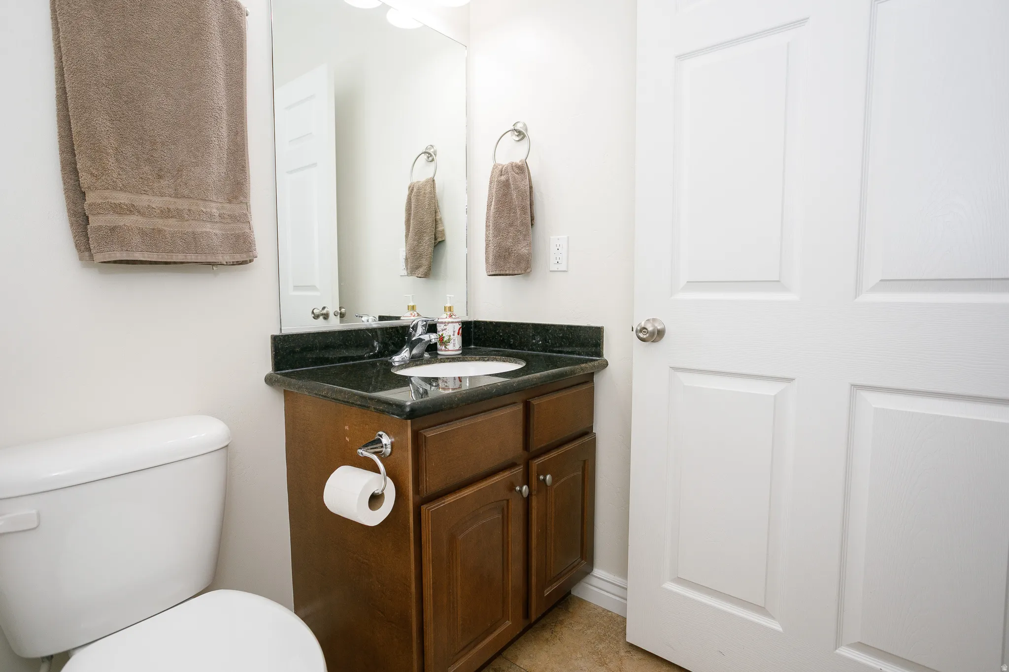 Dark wood-finish vanity with a dark countertop and undermount sink