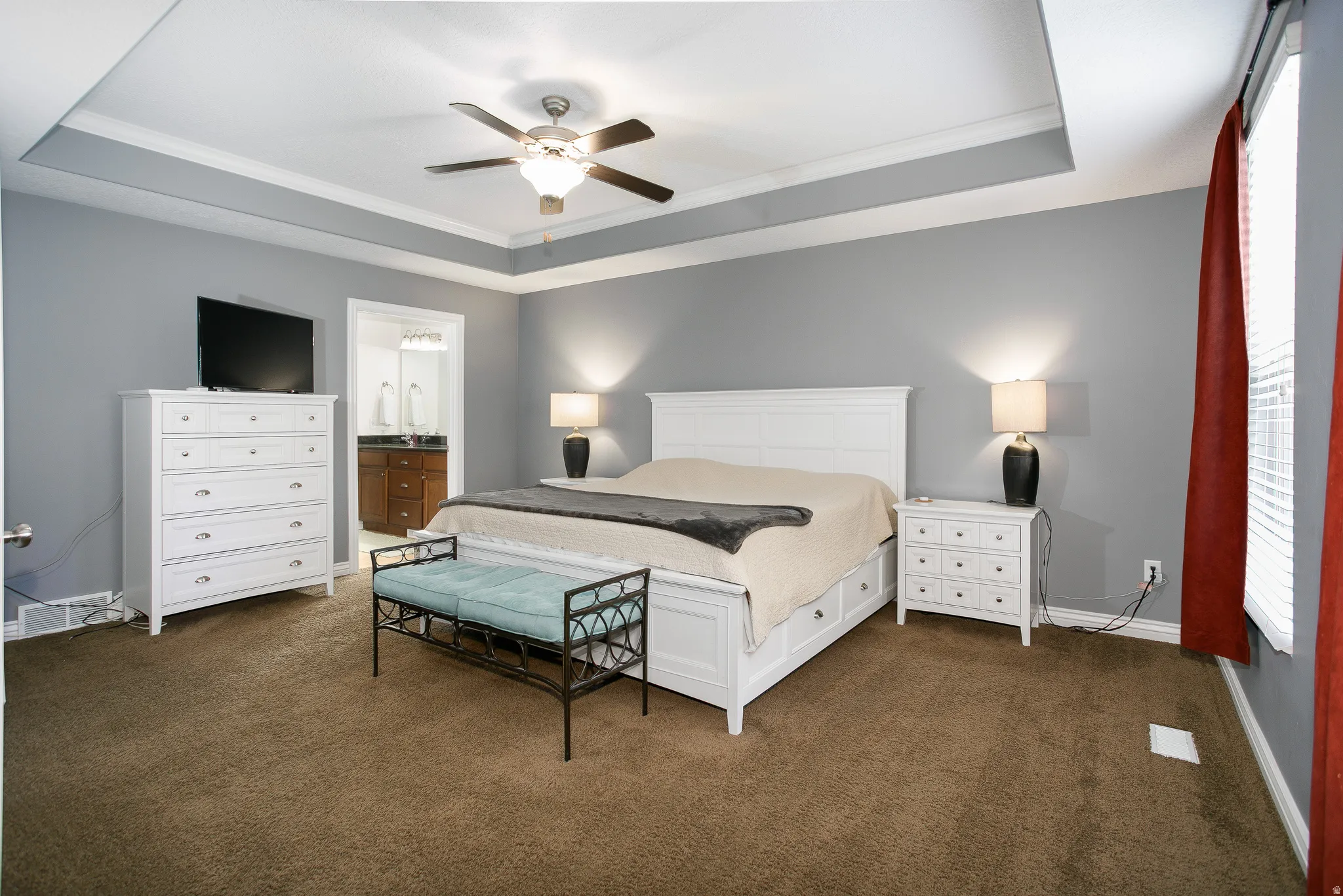 Tray ceiling with crown molding, ceiling fan, and carpeted flooring