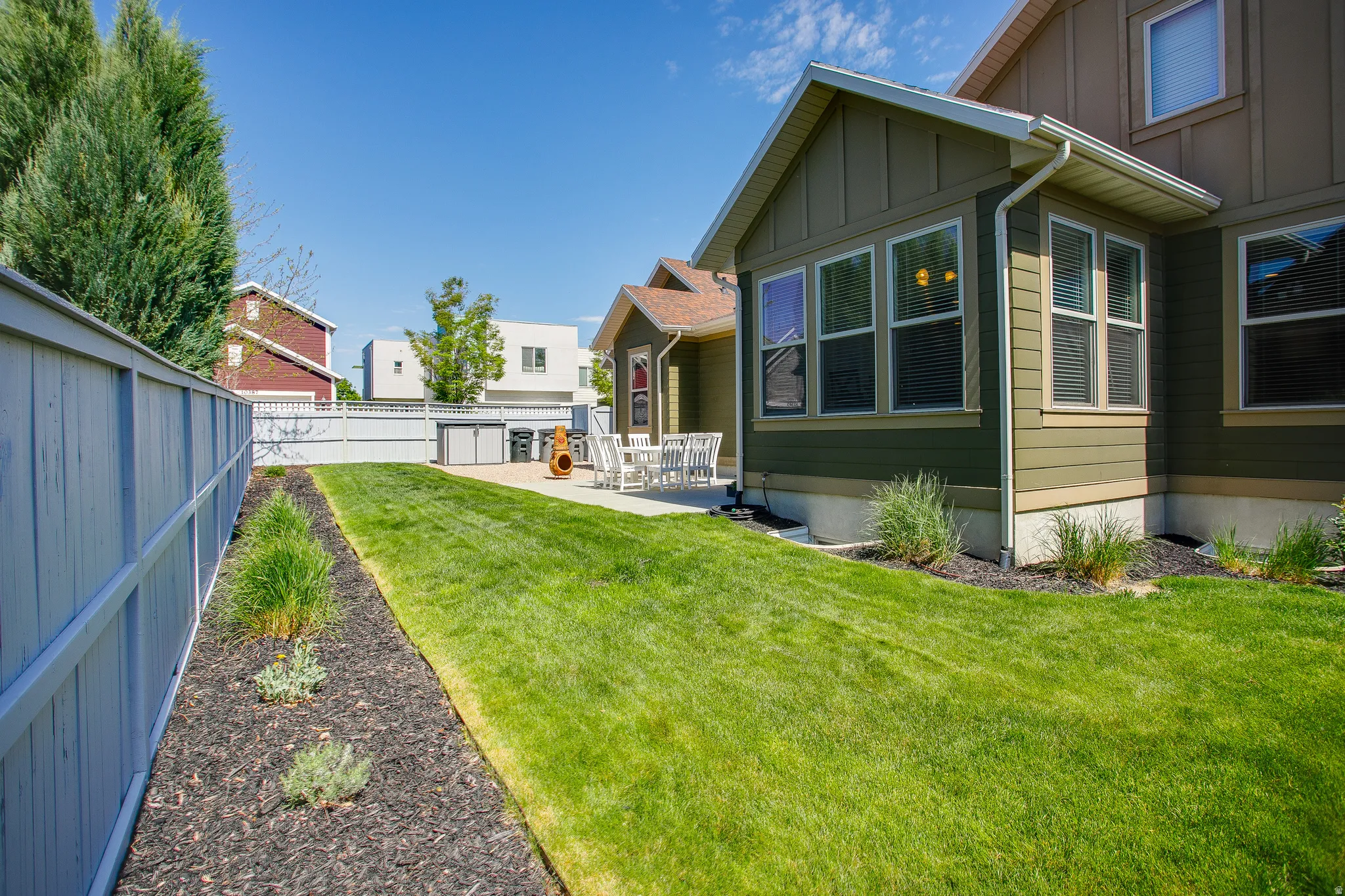 Expansive green lawn with a white privacy fence and a landscaped border