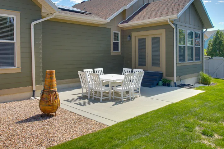 Expansive concrete patio with French doors, surrounded by a manicured lawn and gravel hardscaping