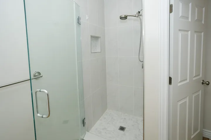 Shower with frameless glass enclosure, tiled walls, and a built-in niche