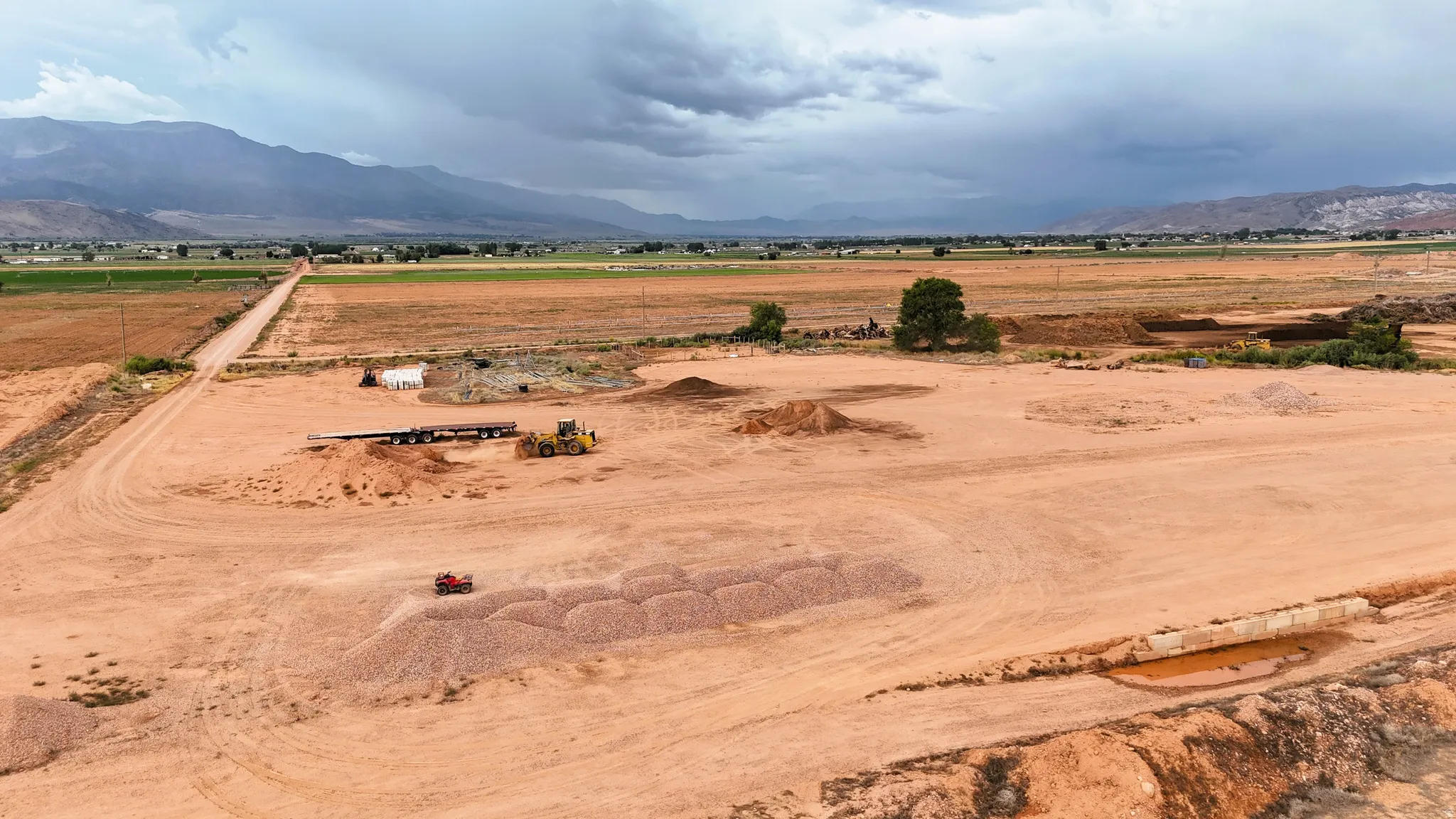Expansive open land with a dirt road, distant mountains, and scattered trees