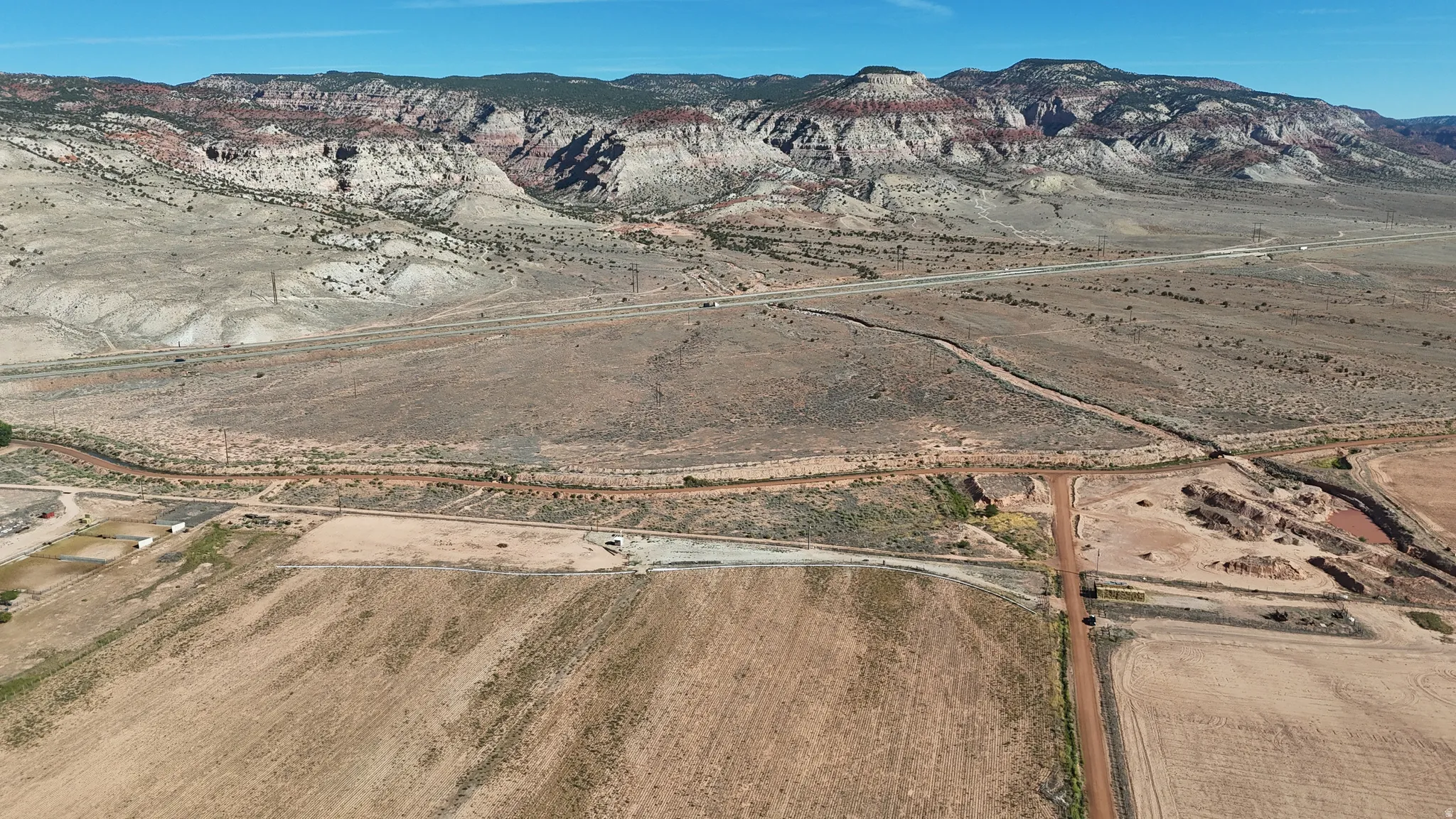 Expansive rural landscape with distant mountainous terrain, a visible roadway, and agricultural fields