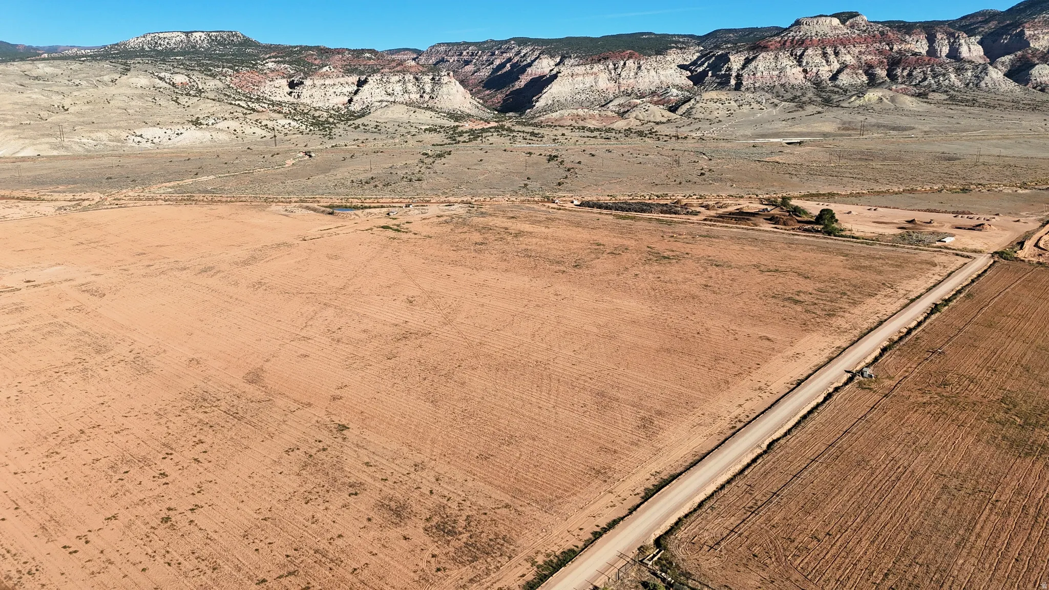 Expansive open land with a dirt road and distant mountainous terrain