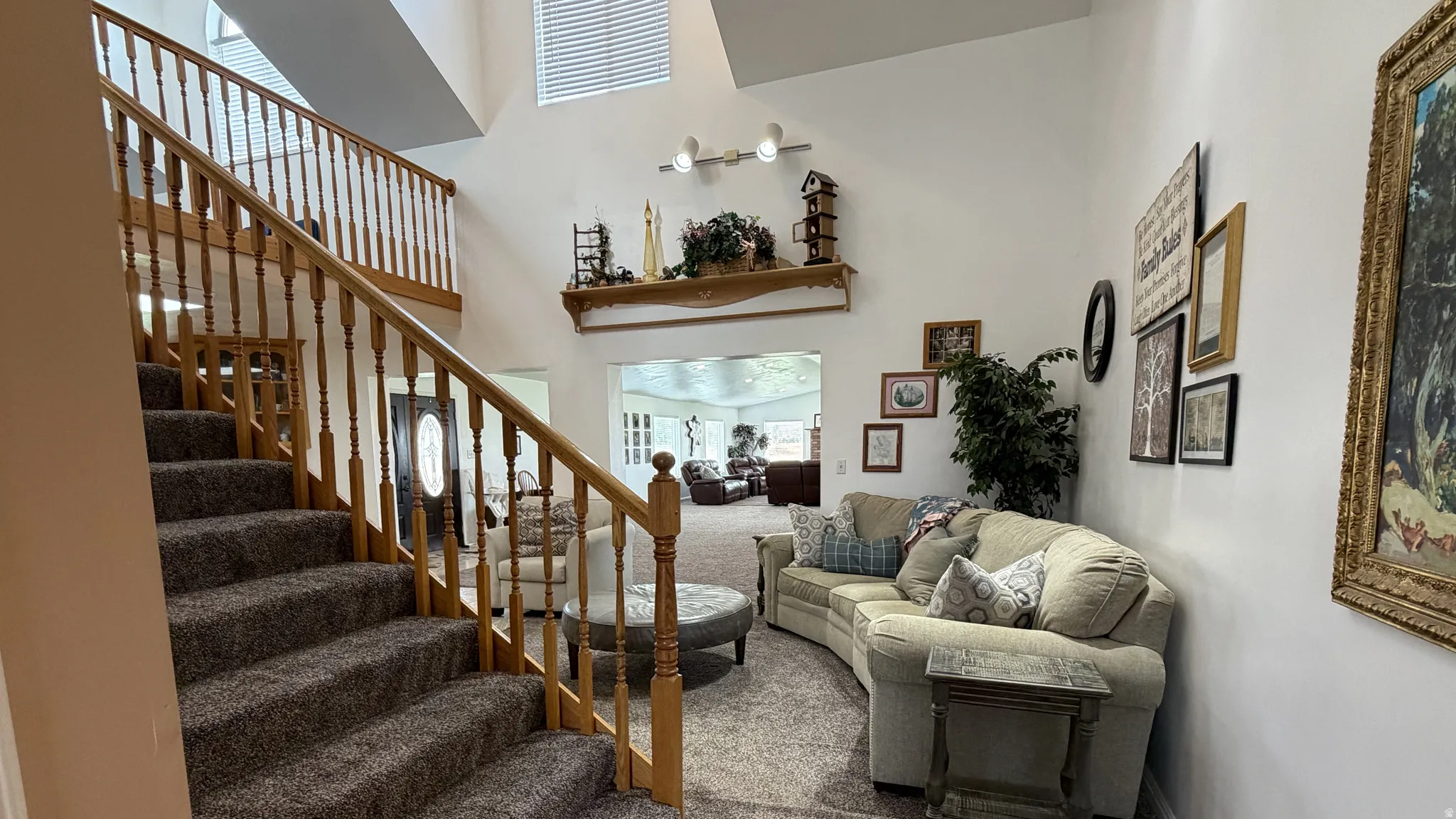 Two-story foyer featuring a carpeted staircase with wood banisters, vaulted ceilings, and upper-level windows