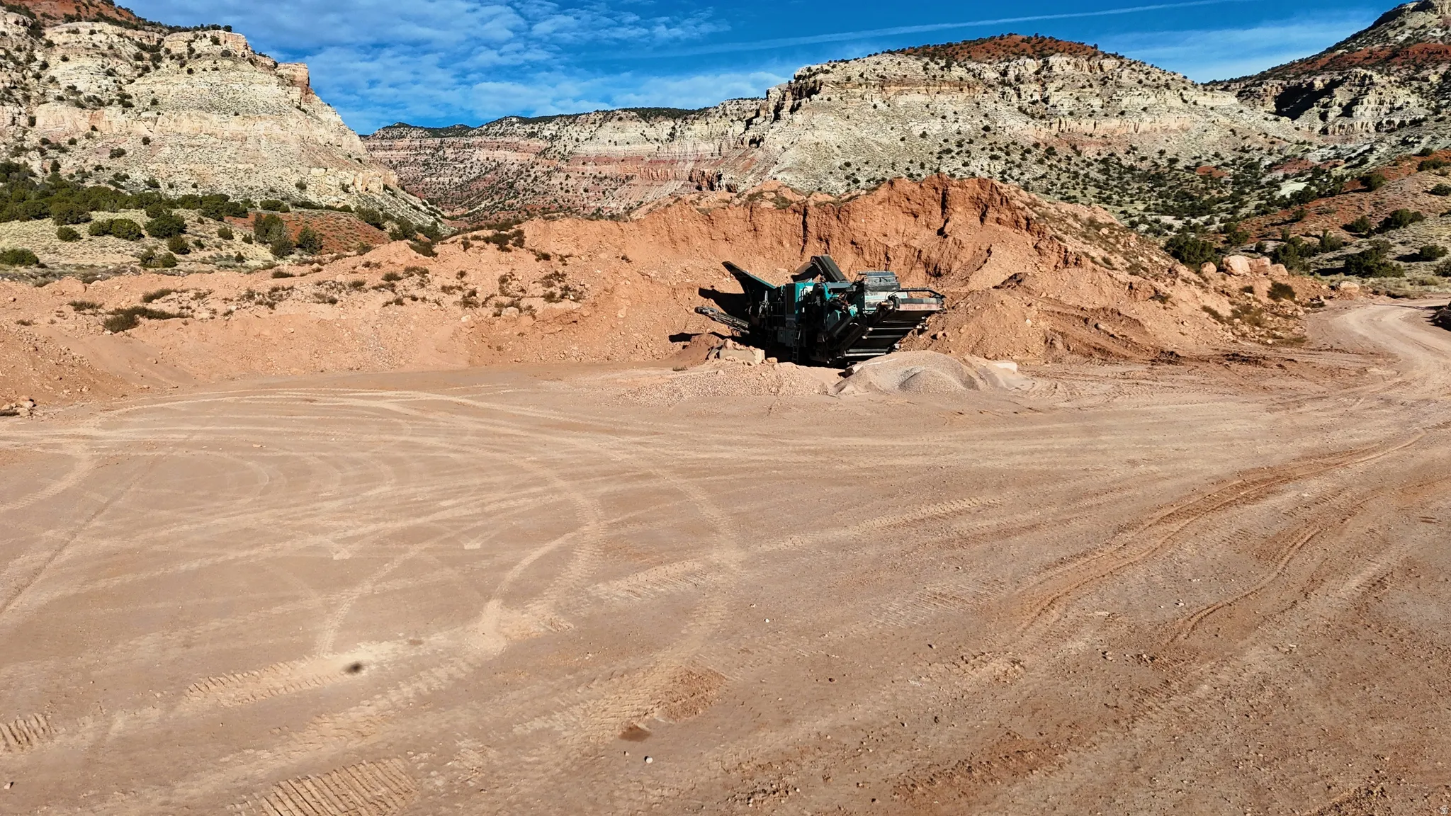 Expansive undeveloped acreage with significant dirt mounds, featuring a clear dirt road, and surrounded by rugged natural rock formations