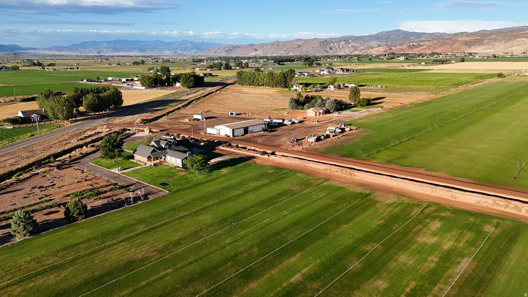 Expansive agricultural land featuring cultivated fields, a primary residence with an attached garage, and multiple outbuildings