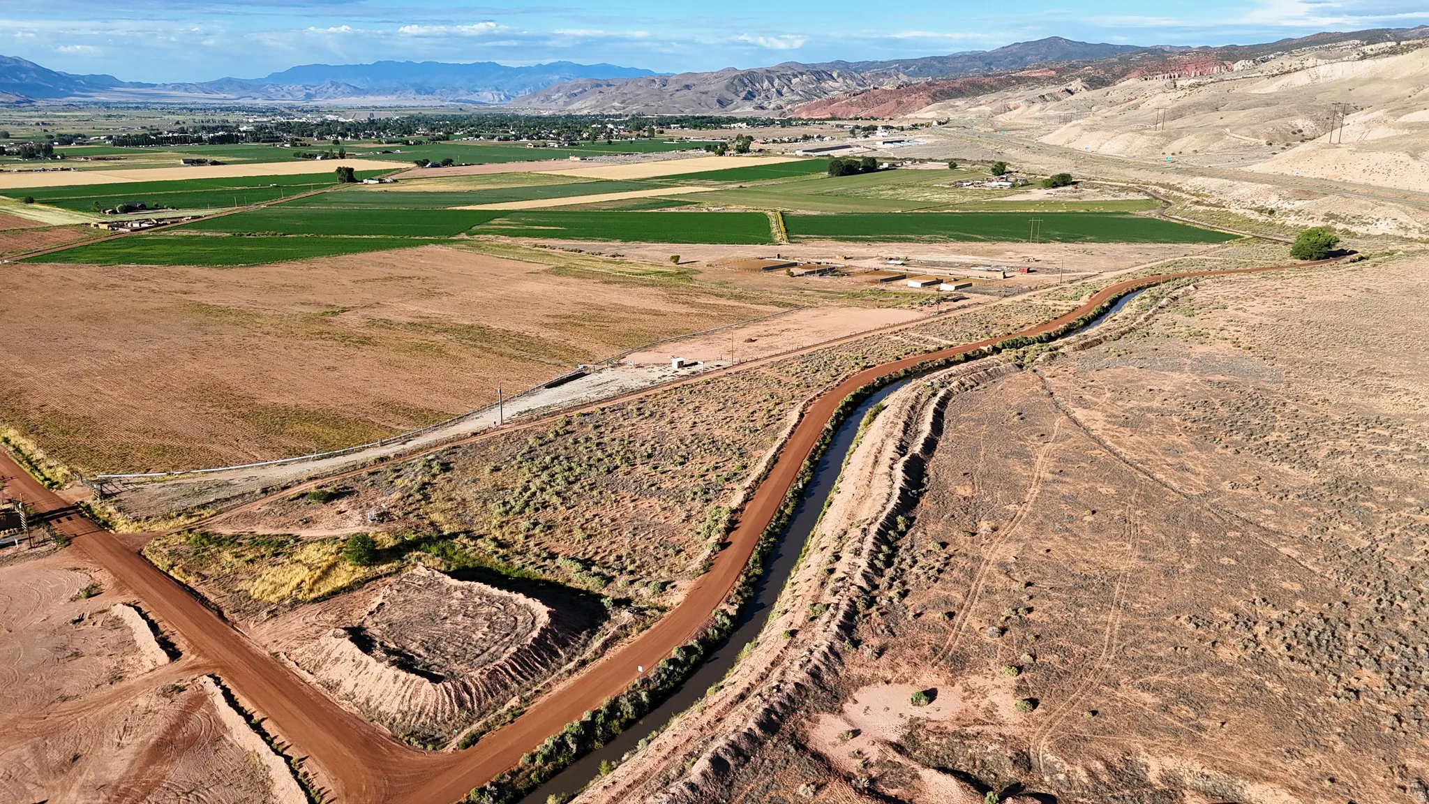 Expansive rural landscape featuring a winding waterway and distant mountains