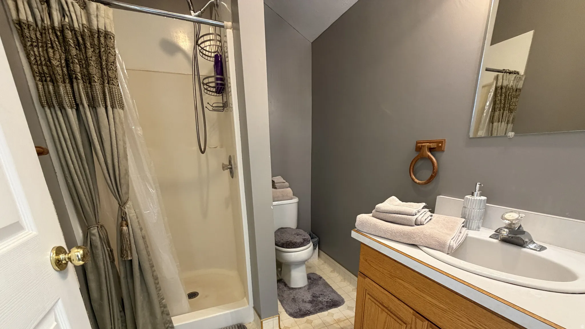 White shower enclosure with a chrome shower head and integrated storage