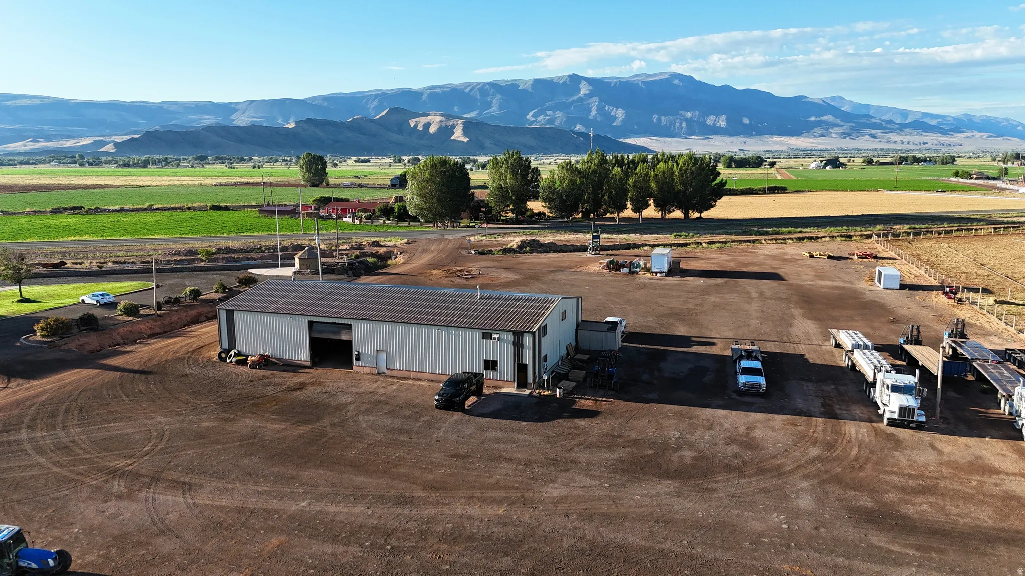 Metal-sided building with a roll-up door, expansive gravel lot, and concrete pad
