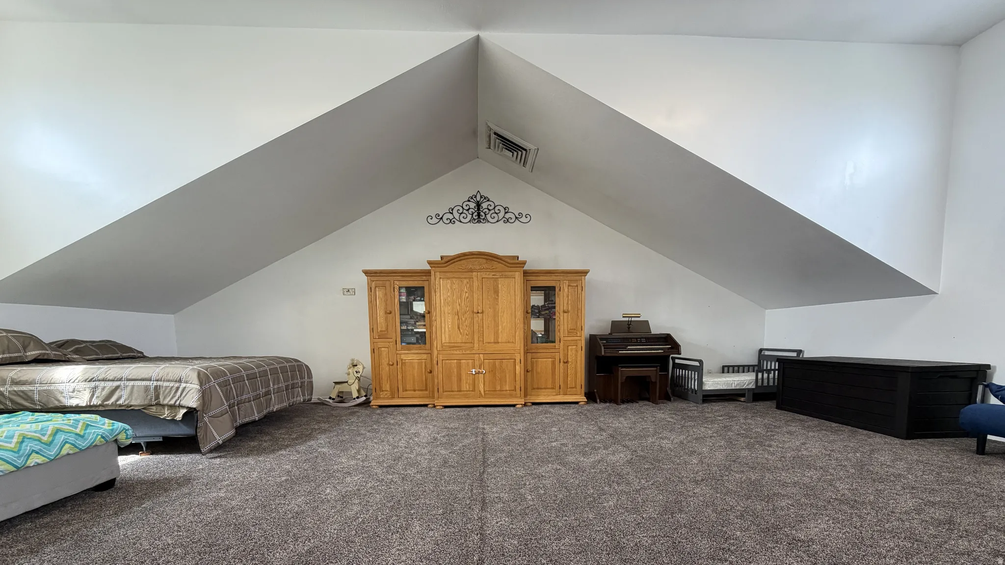Vaulted ceilings with exposed beams, recessed lighting, and soft gray carpeting