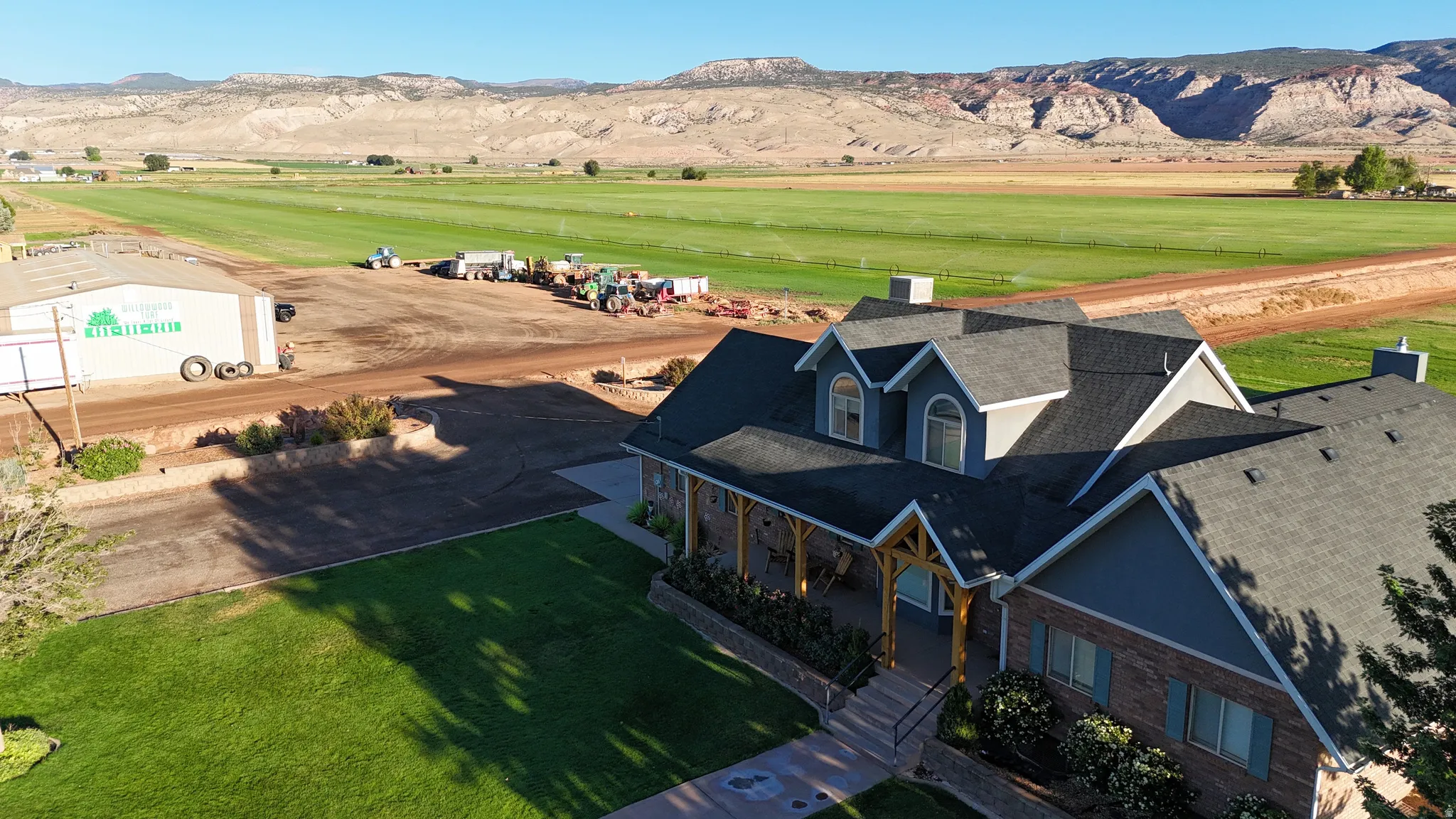 Multi-gabled roofline, stone and siding exterior, expansive front porch with wood columns, and a large manicured lawn