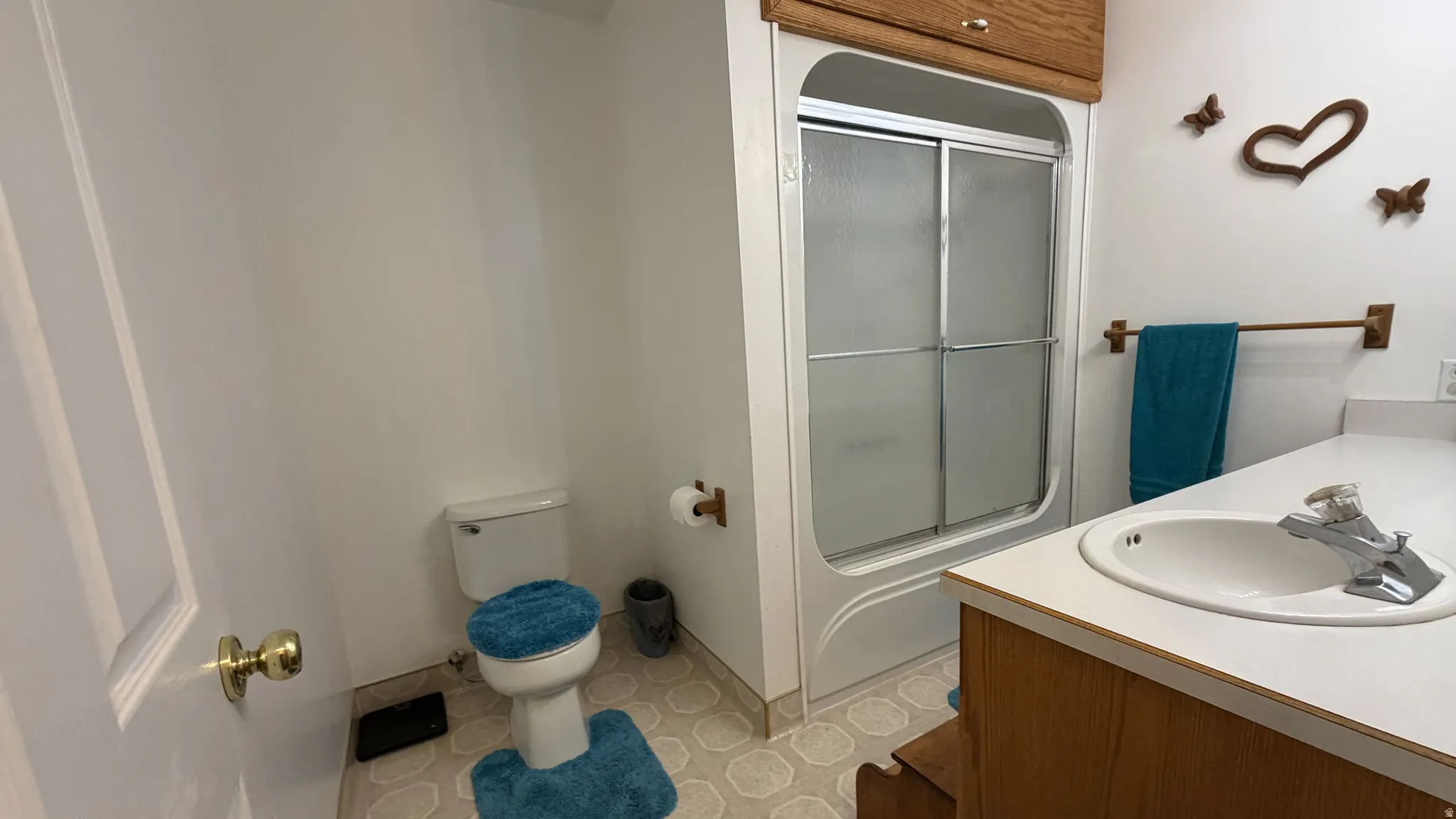 Bathroom featuring a shower with sliding glass doors, a vanity with a drop-in sink, and a toilet