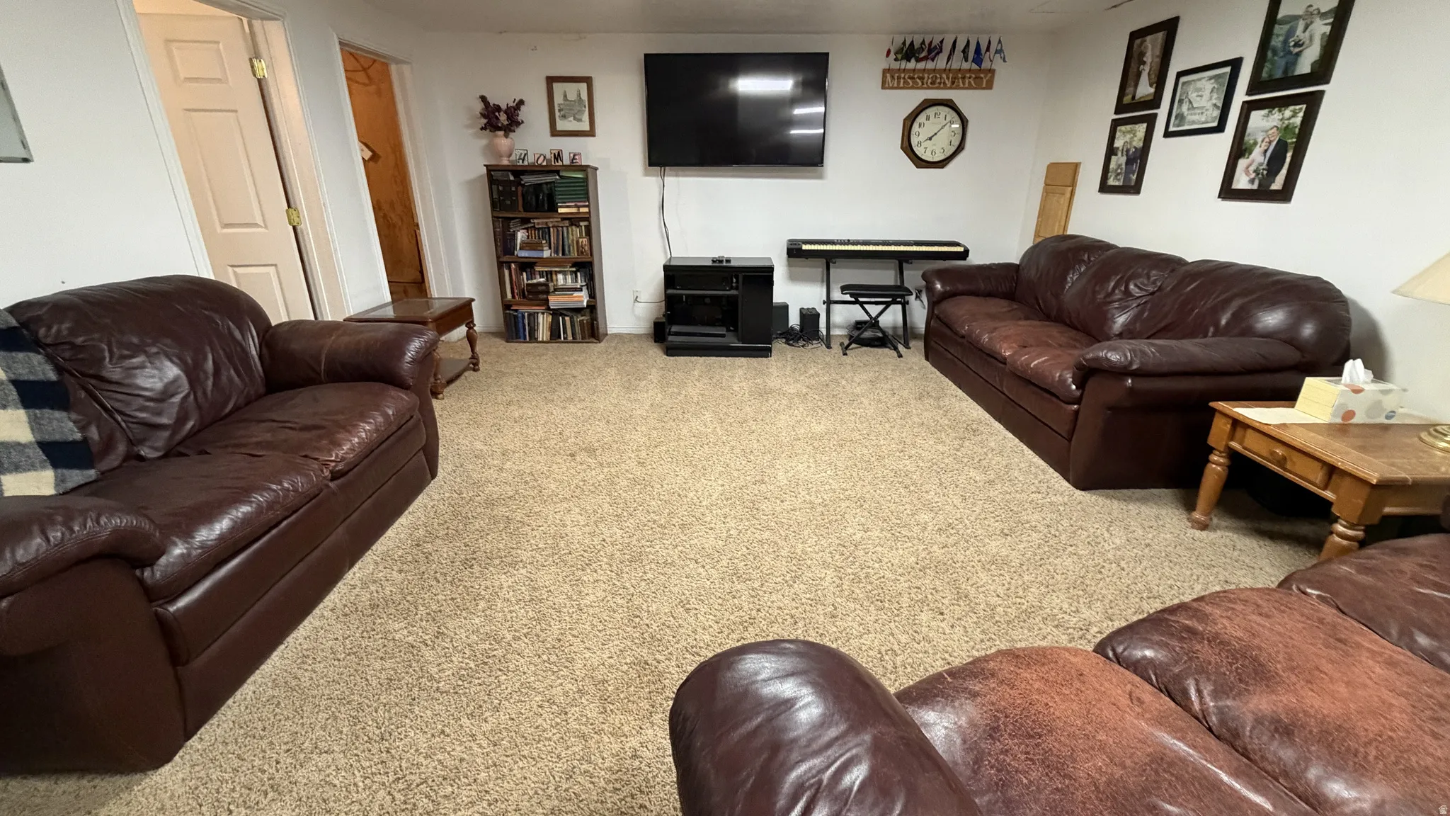 Carpeted recreation room with white walls and overhead lighting