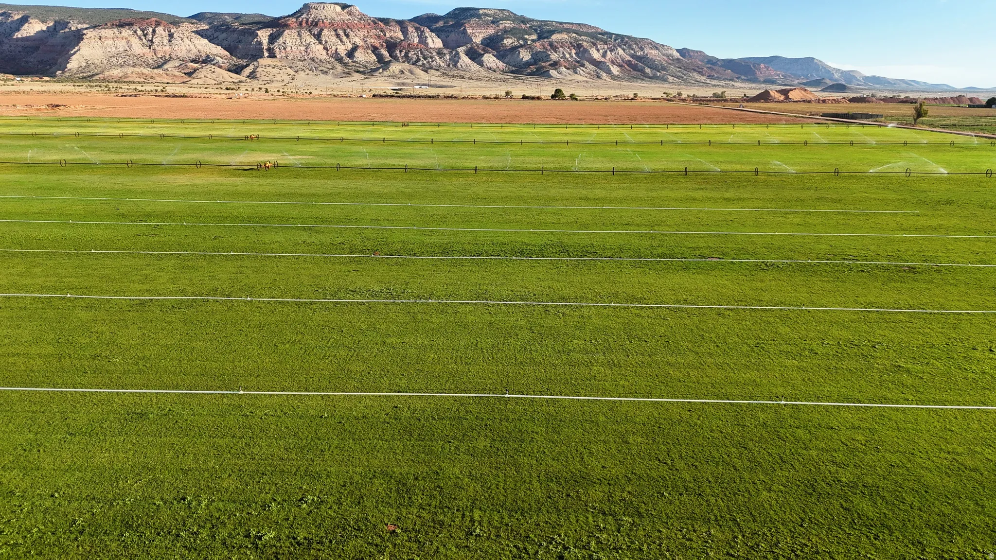 Expansive green acreage with irrigation lines and a distant mountainous backdrop